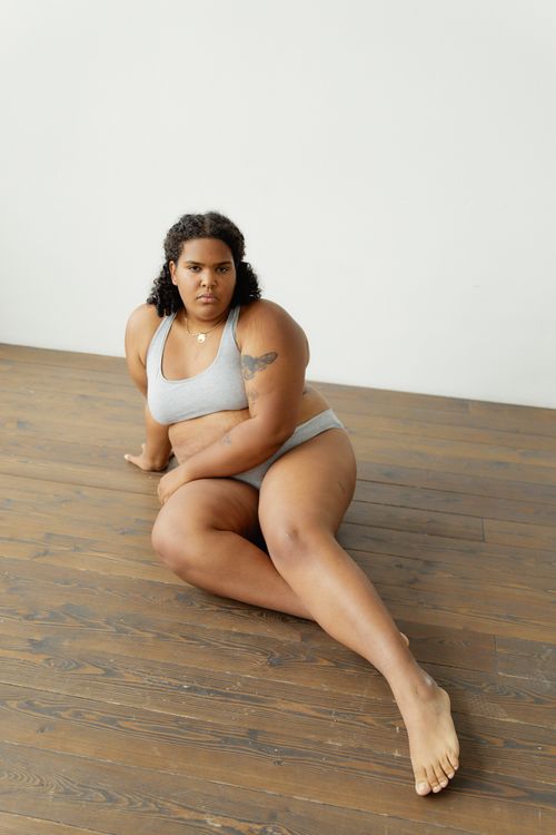 Free Empowering and stylish plus-size model posing confidently in modern lingerie indoors. Stock Photo