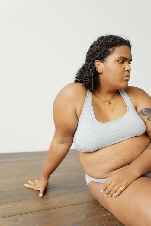 Free Empowering portrait of a plus-size woman in gray lingerie, promoting body positivity. Stock Photo