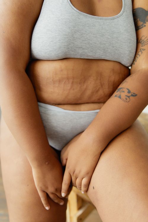 Free Close-up of a plus size woman with tattoos showcasing body positivity in gray underwear. Stock Photo