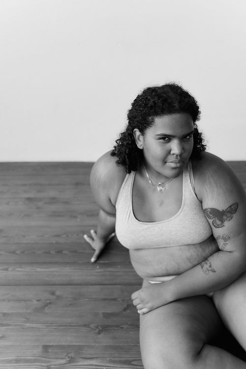 Free Graceful black and white portrait of a plus-size model embracing body positivity while posing on a wooden floor. Stock Photo