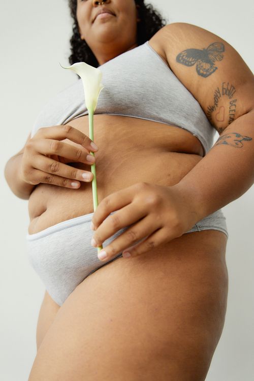 Free A plus size woman holding a white flower, embracing body positivity and confidence in lingerie. Stock Photo