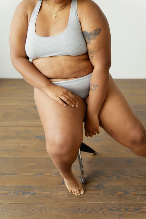 Free Body positive plus size woman posing confidently in gray lingerie indoors. Stock Photo