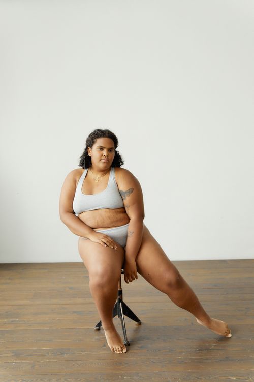 Free Portrait of a confident plus size woman in lingerie posing against a minimalistic background. Stock Photo