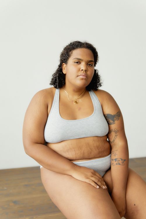 Free Portrait of a confident plus-size woman in gray lingerie, showcasing body positivity and empowerment. Stock Photo