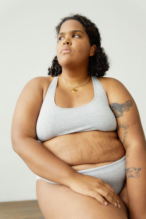 Free Portrait of a confident plus-size African American woman in grey lingerie embodying body positivity indoors. Stock Photo