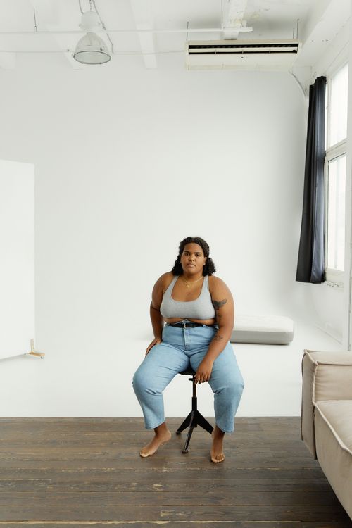 Free Confident plus-size woman sitting on stool in modern studio environment. Stock Photo