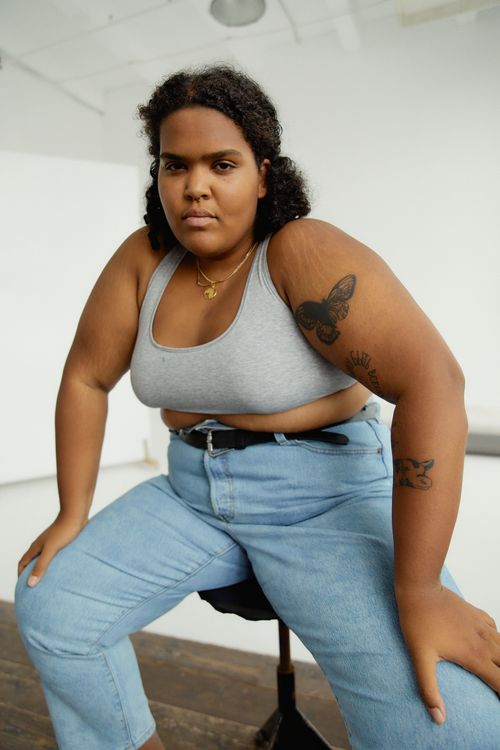 Free Portrait of a confident plus-size woman in casual attire, embracing body positivity indoors. Stock Photo