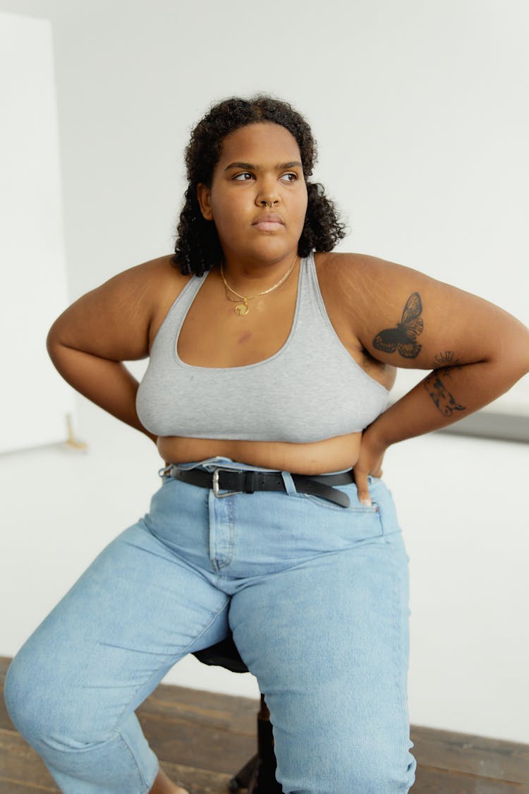 Woman Gray Bra And Denim Jeans Sitting On A Stool