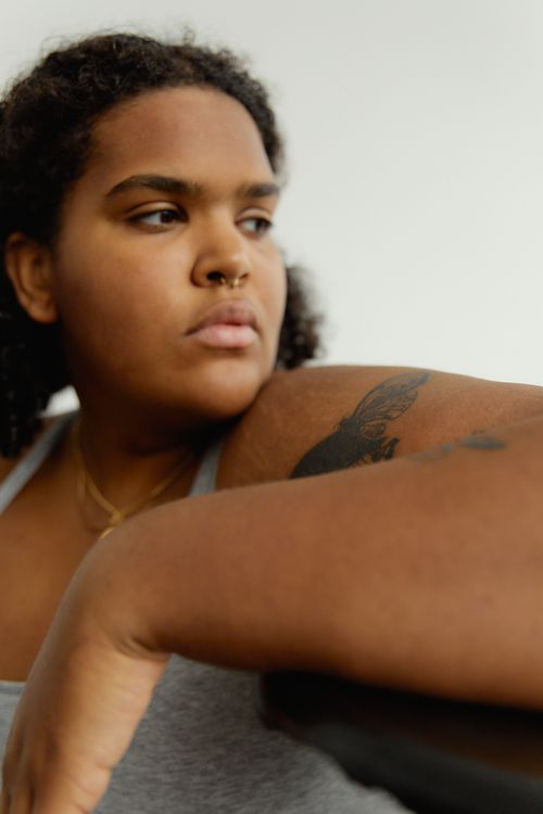 Free Close-up portrait of a tattooed woman with a thoughtful expression indoors. Stock Photo