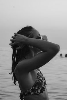 Artistic black and white photo of a woman at the beach, capturing a serene summer moment. Perfect for lifestyle and travel concepts.