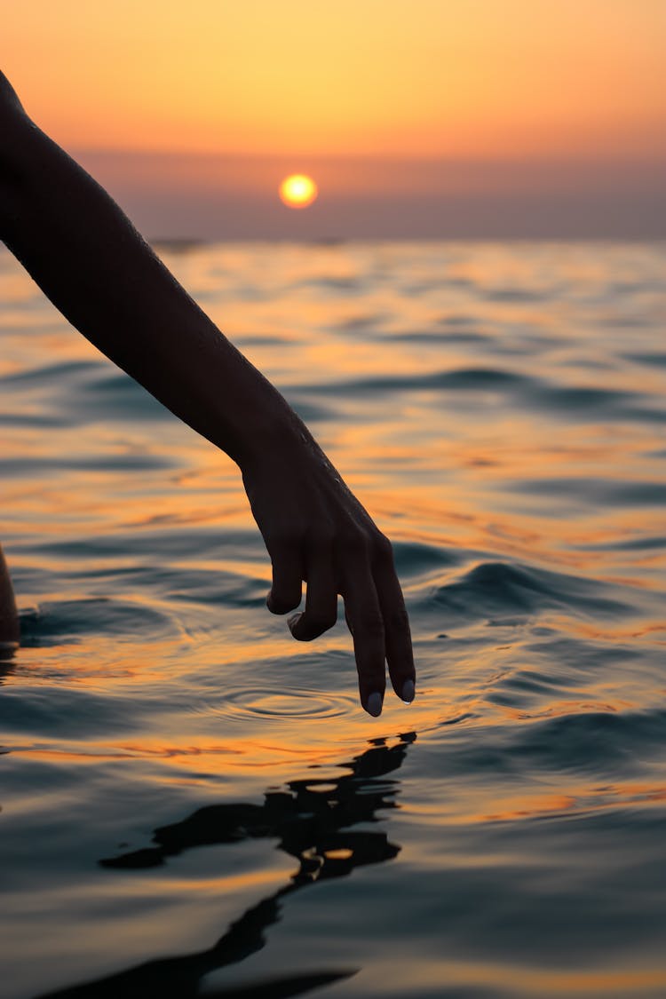 Woman Hand Touching Sea Water On Sunset