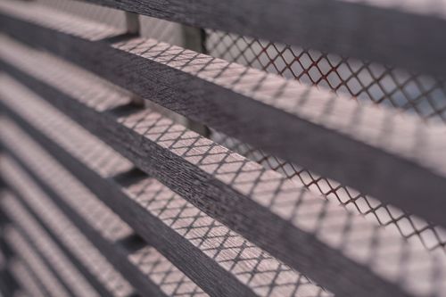 Free Detailed photo of a slatted wooden fence creating geometric shadow patterns. Stock Photo