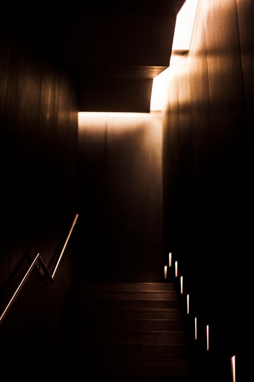 Free A dimly lit modern staircase with dramatic lighting and shadows, creating a mysterious indoor ambiance. Stock Photo