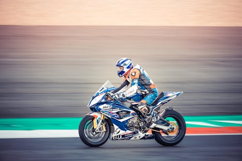 Man in Blue and White Jacket Riding Blue and White Sports Bike