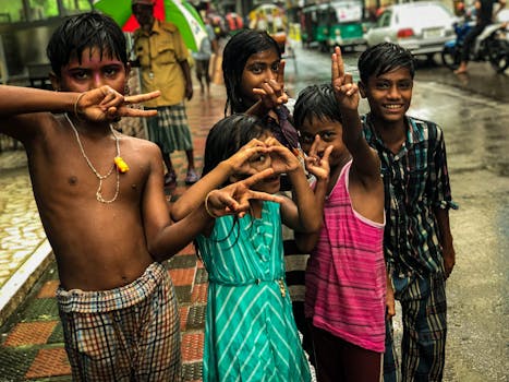 Group of children playing and gesturing on a rainy city street, expressing joy and childhood fun.