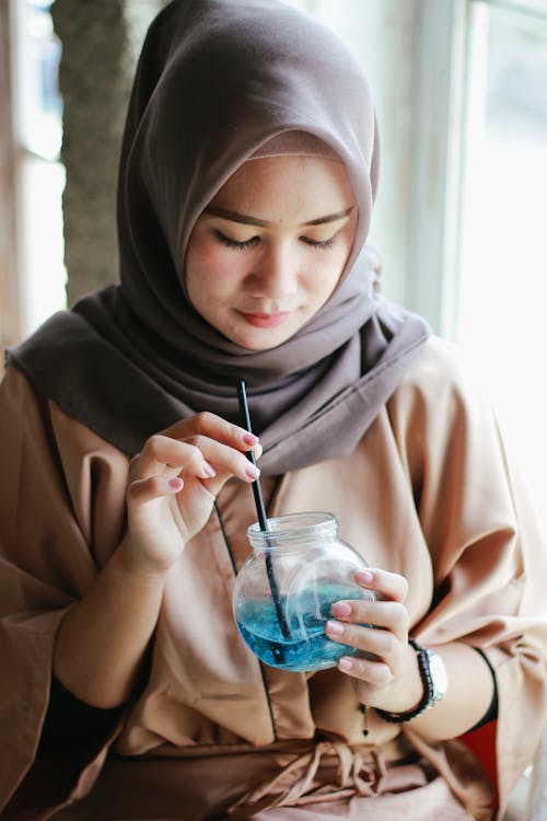 Free Woman in Brown Hijab Holding a Drinking Glass Stock Photo