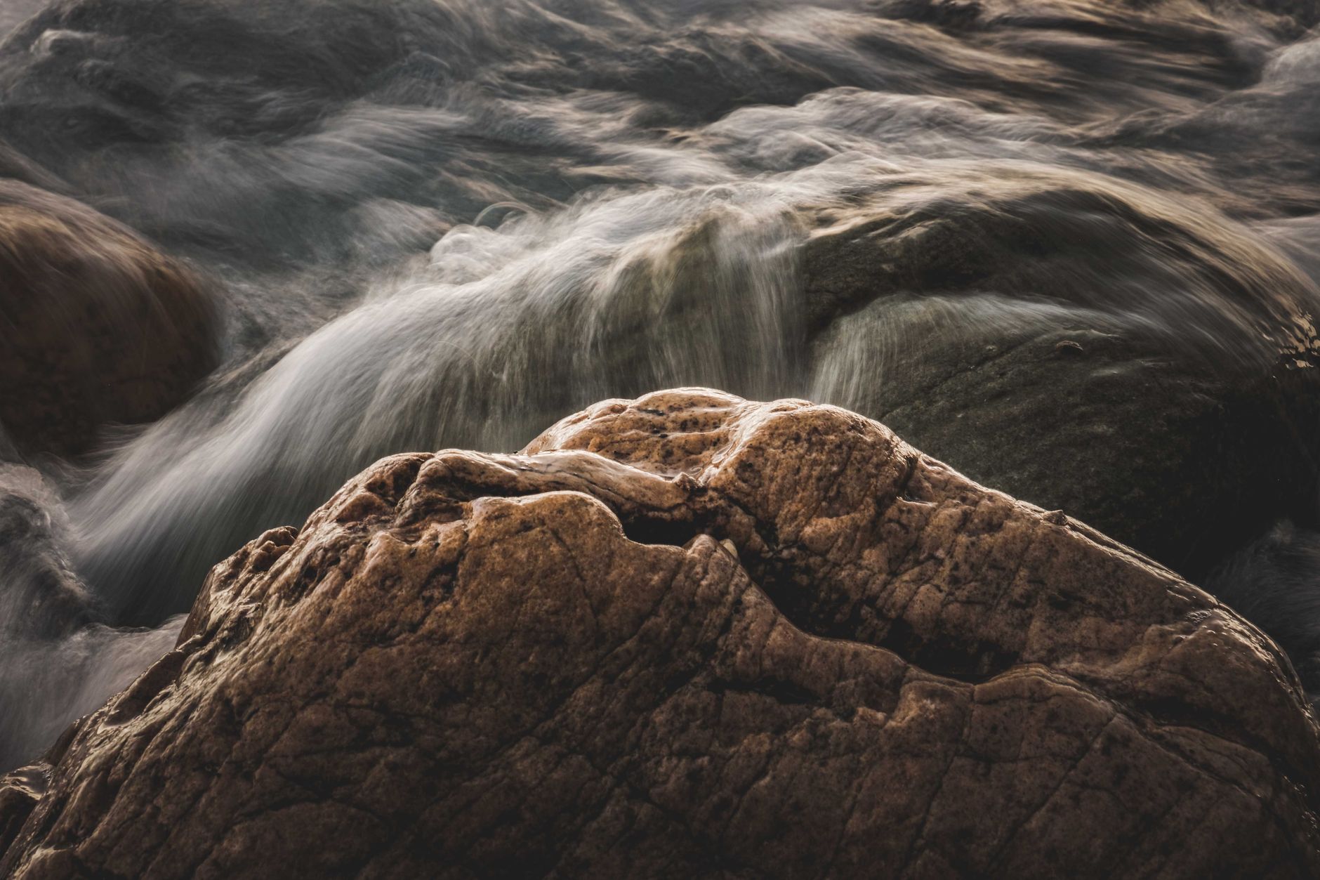手機慢門拍攝水流絲滑:穩定支撐與曝光策略全解 Long exposure of water cascading over rugged boulders, capturing nature's power.