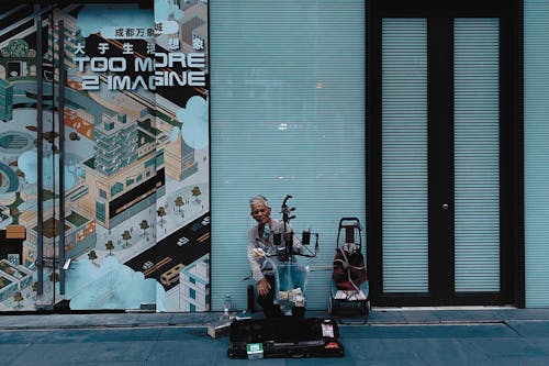 Street Musician Sitting on Sidewalk