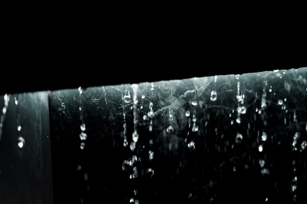 captivating close up of water droplets cascading in dark setting