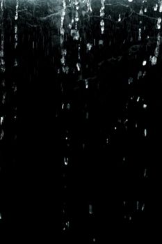 Vertical cascading raindrops on a black background create a dramatic and moody effect.