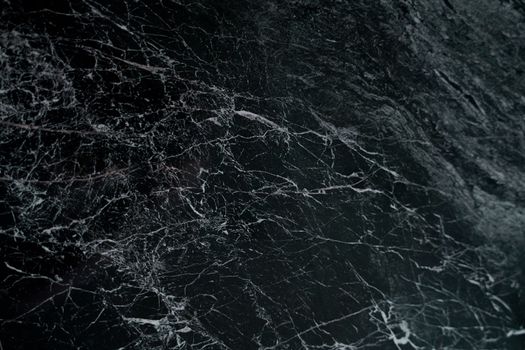 Intricate pattern on a dark marble surface, showcasing natural veins and textures.