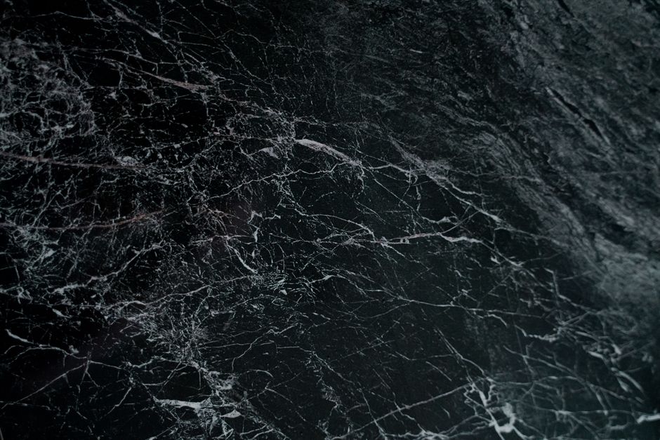 Intricate pattern on a dark marble surface, showcasing natural veins and textures.