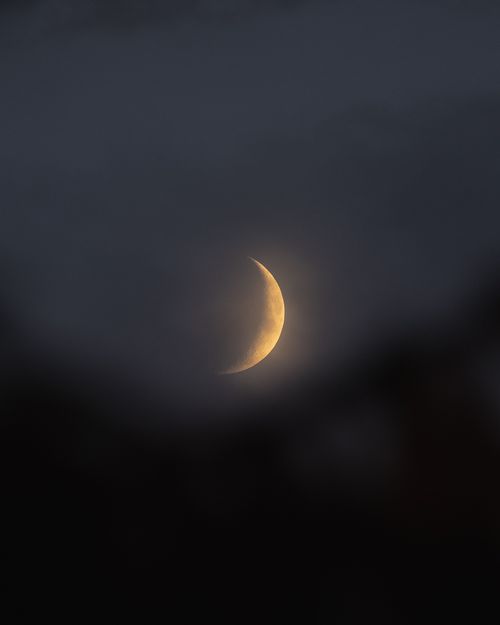 Free A serene crescent moon glowing softly amid the mist in a tranquil night sky scene. Stock Photo
