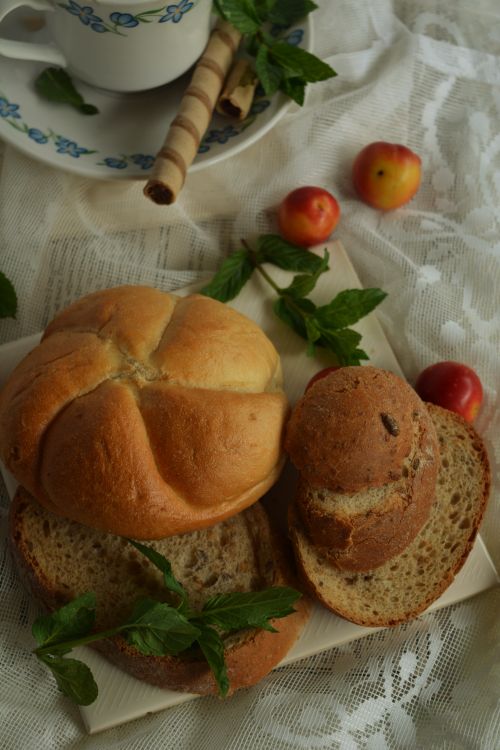 Free Close-up of rustic bread, fresh plums, and mint leaves on a lace tablecloth with a teacup in Bulgaristan. Stock Photo
