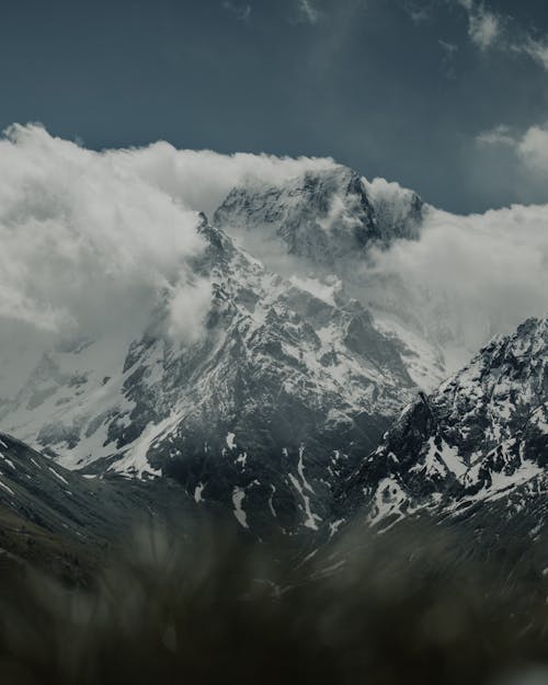 Landscape of Rocky Snowcapped Mountains with the Peaks among the Clouds 