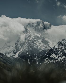 Explore the breathtaking snowcapped peaks of the Dombay mountains, surrounded by dramatic clouds.