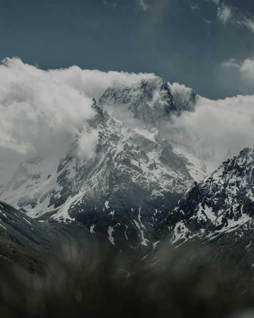 Free Explore the breathtaking snowcapped peaks of the Dombay mountains, surrounded by dramatic clouds. Stock Photo