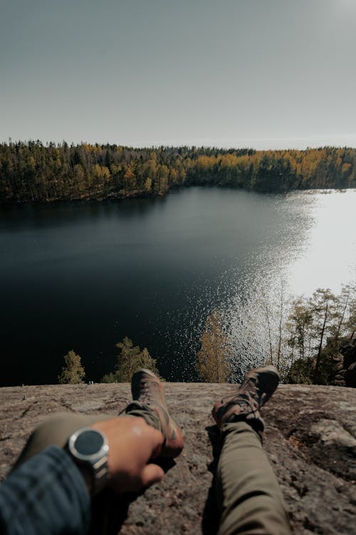 Free Hiker on Rock Looking at Lake and Forest Stock Photo