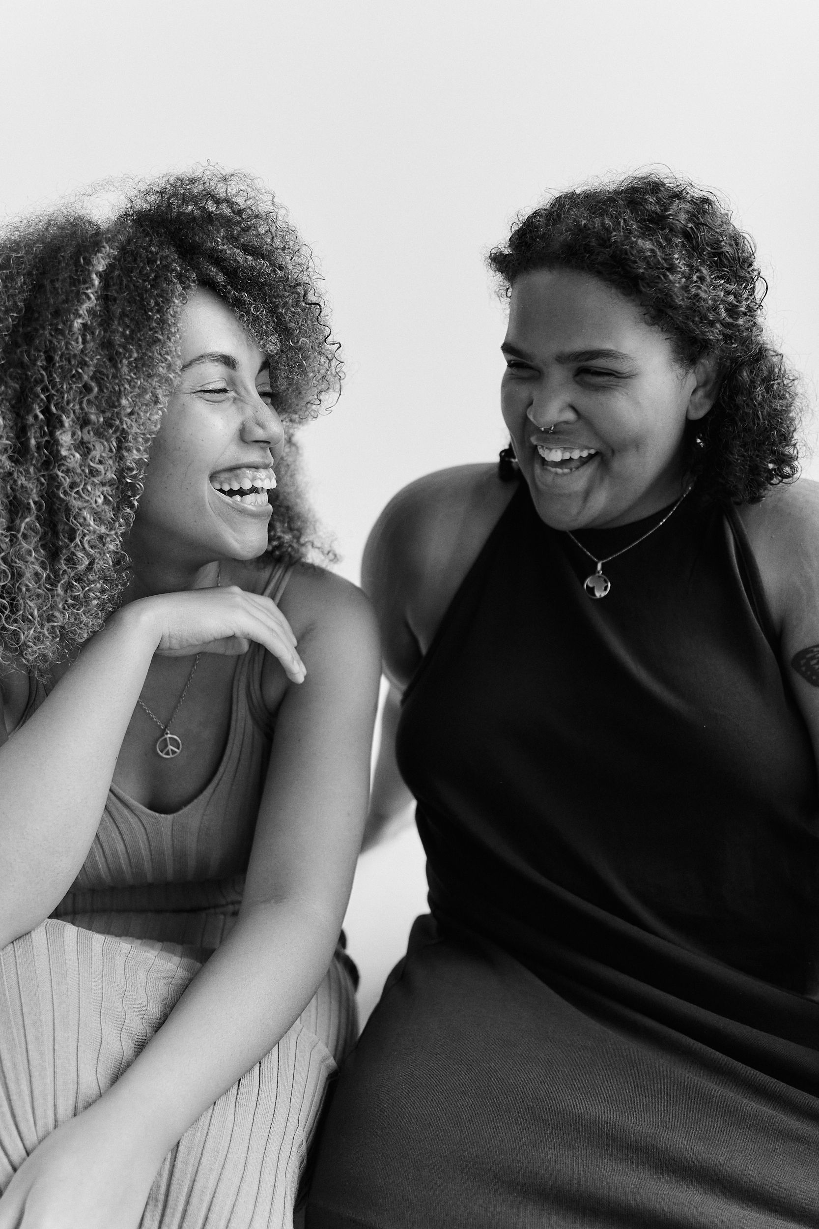 A warm black and white portrait capturing joy between two friends sharing a moment of laughter