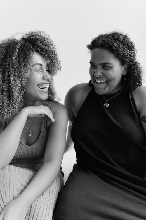 一緒に笑っている2人の女性のグレースケール写真