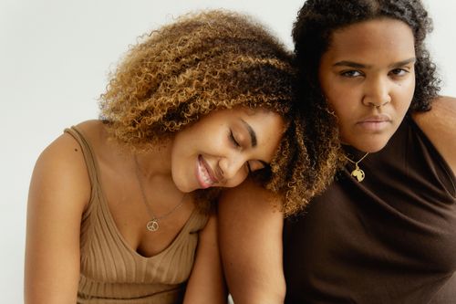 Free Close-up portrait of two women with one leaning on the other's shoulder, expressing friendship. Stock Photo