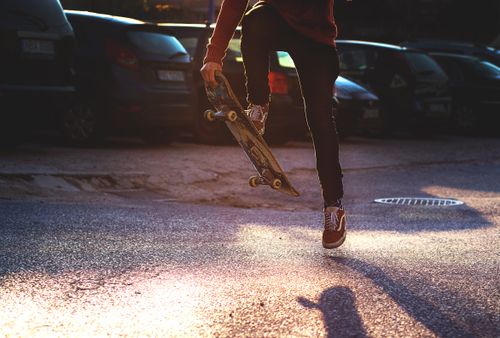 Free Young skateboarder performing an energetic trick in the urban street during sunset. Stock Photo