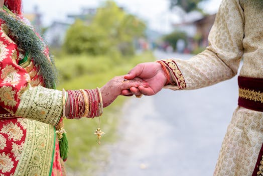 A couple holding hands in traditional Indian attire, symbolizing love and unity.