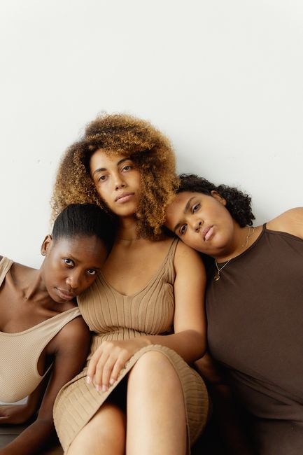 A touching portrait of three diverse African American women embracing unity and sisterhood indoors.