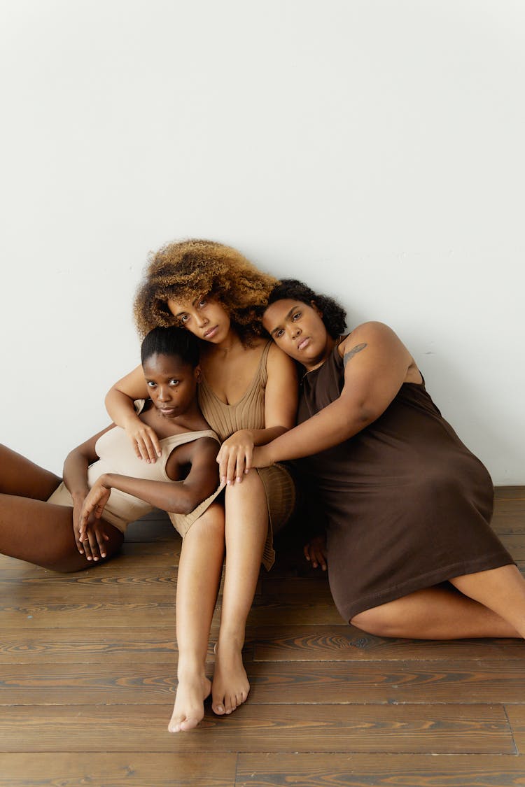 Group Of Friends Embracing And Sitting Together On A Wooden Floor