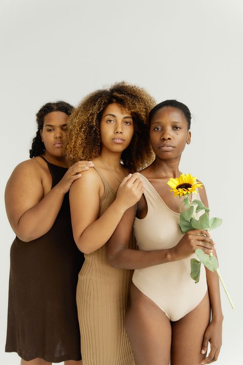 Free Three diverse women pose elegantly in nude fashion with a sunflower, showcasing diversity and natural beauty. Stock Photo