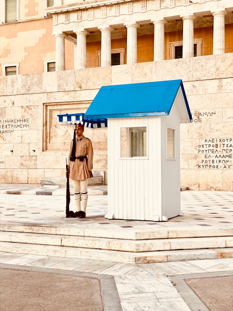 A Greek Presidential Guard Standing While Holding A Gun During The Day