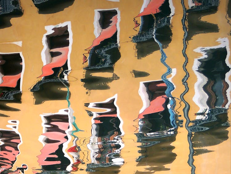 Reflection Of A Yellow Residential Building In Water Surface