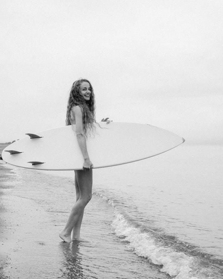 Woman Holding Surfboard Walking On A Beach