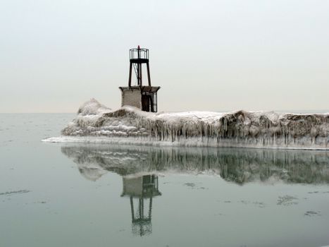 A serene winter scene featuring an icy lighthouse reflecting on a frozen sea.