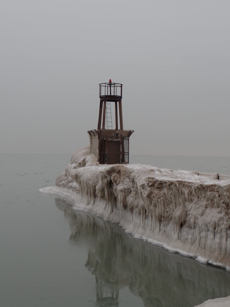 Sea Signal Tower Standing On Pier Covered By Ice And Snow