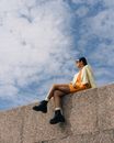 A Woman Sitting on a Wall with Feet Dangling