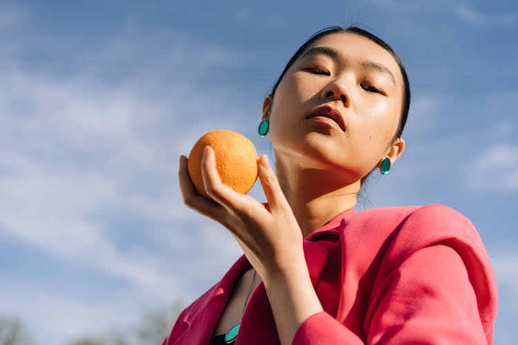 Woman In Pink Blazer Holding A Fruit