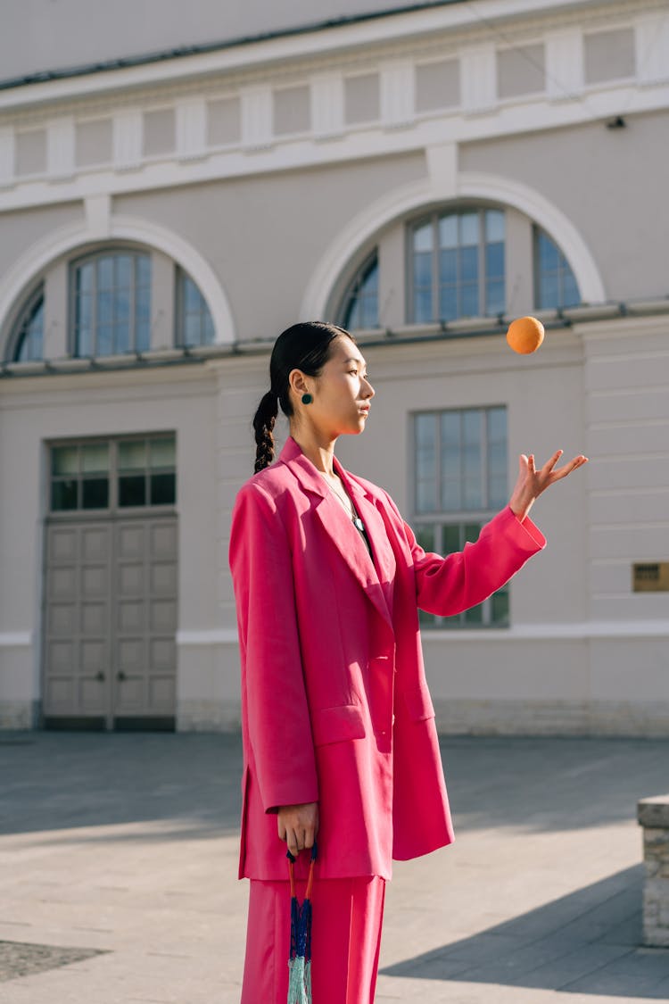 Woman In Pink Suit Throwing Tangerine