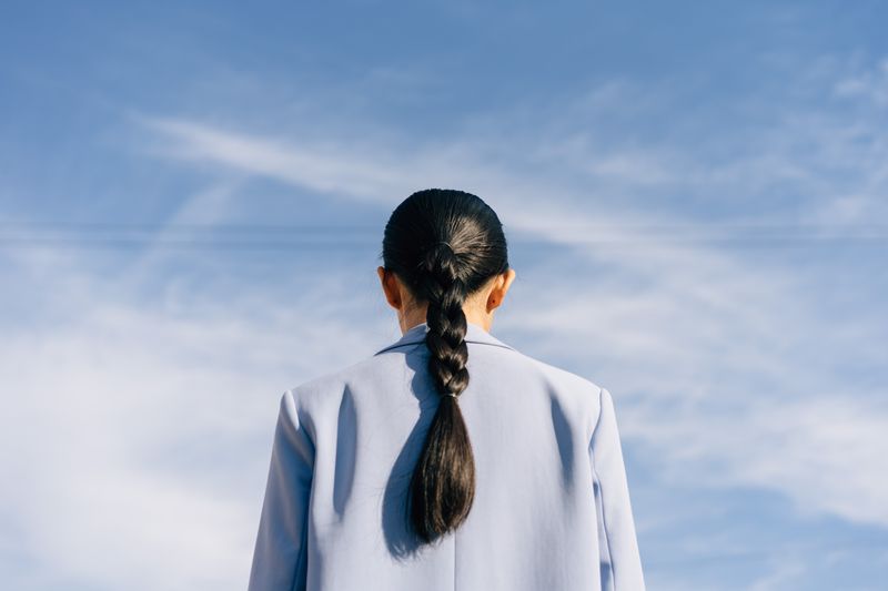 Back view of a woman with a long braid against a blue sky