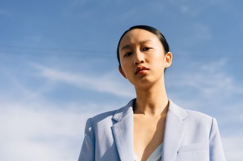 Free Low-angle shot of a woman in a blazer under a bright blue sky, exuding confidence and style. Stock Photo